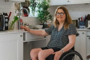 Woman using a wheelchair at an accessible kitchen sink at home, NDIS in home support