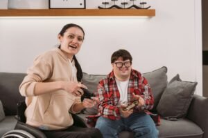 Two housemates in a SIL house relaxing on the sofa playing video games